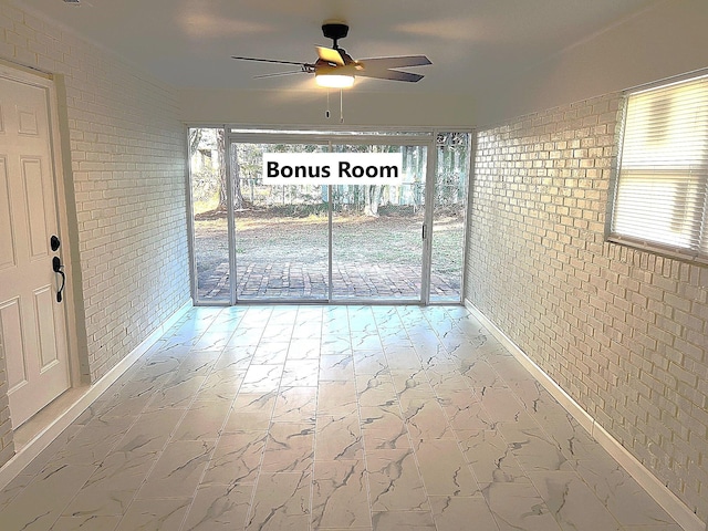 interior space with ceiling fan and brick wall