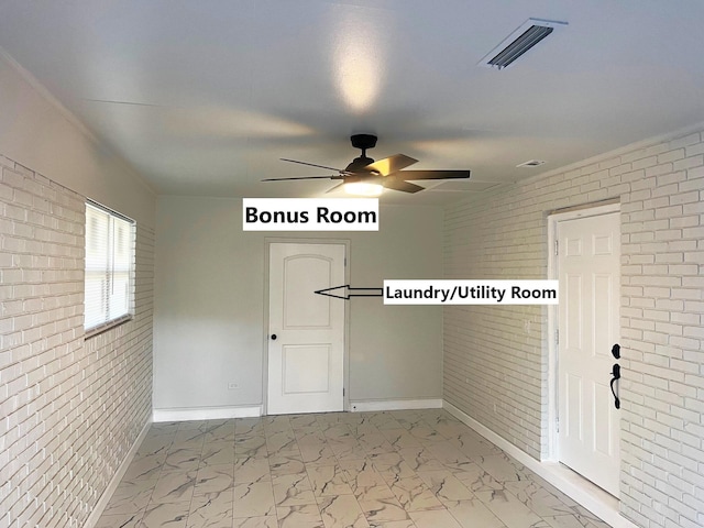 unfurnished room with ceiling fan and brick wall