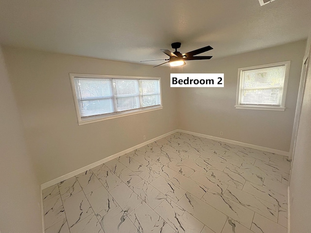 spare room with ceiling fan and a healthy amount of sunlight