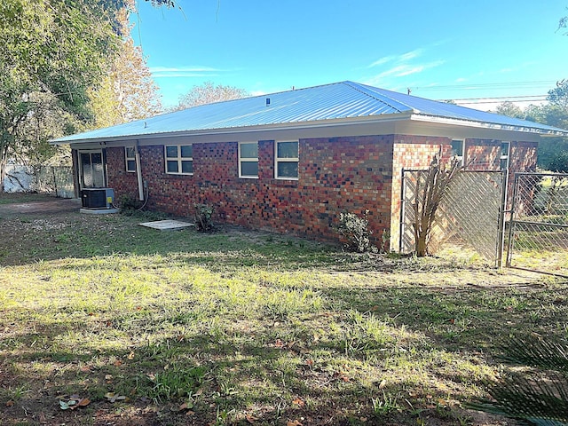 rear view of property with central AC unit and a lawn