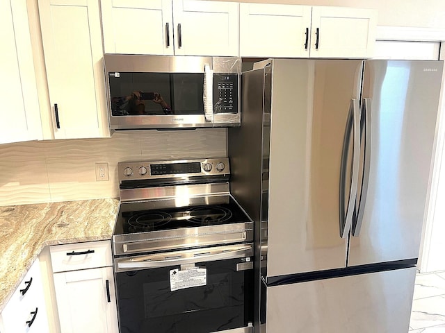 kitchen with light stone counters, white cabinetry, appliances with stainless steel finishes, and tasteful backsplash