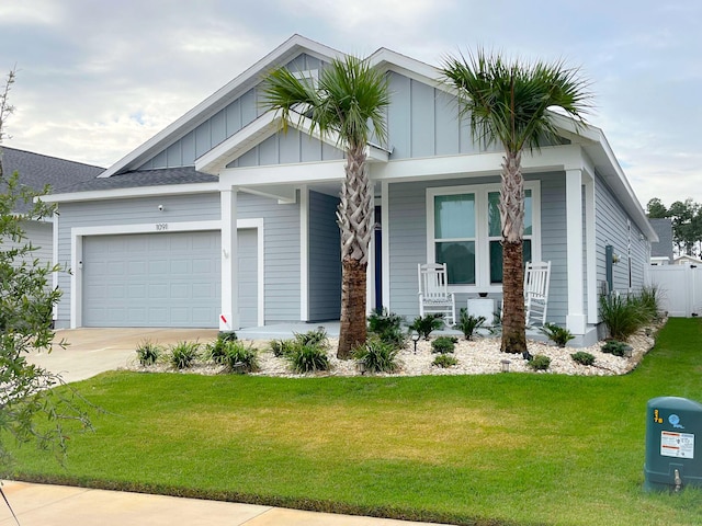 view of front of home featuring a front yard, covered porch, and a garage