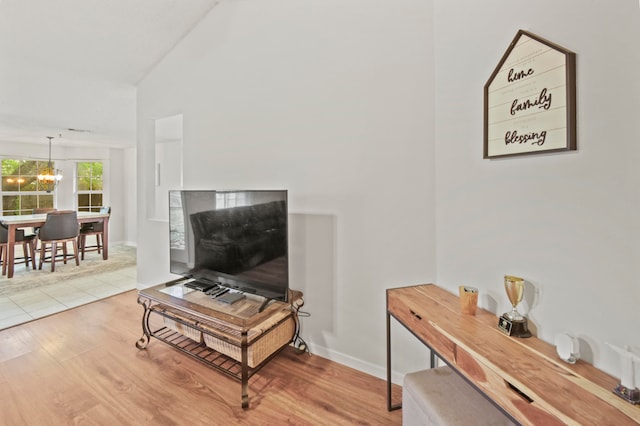 living room with light wood-type flooring, lofted ceiling, and an inviting chandelier