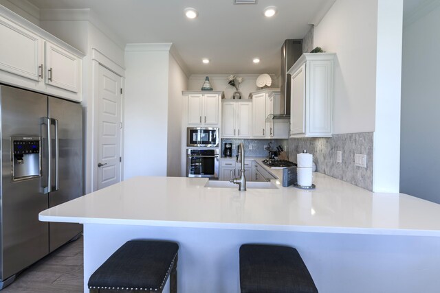 kitchen featuring white cabinetry, sink, kitchen peninsula, appliances with stainless steel finishes, and a kitchen breakfast bar