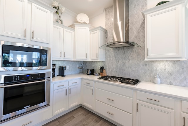 kitchen featuring stainless steel appliances, wall chimney exhaust hood, white cabinets, and light wood-type flooring