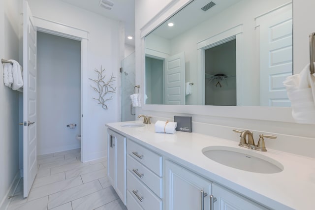 bathroom featuring toilet, vanity, and a shower with door