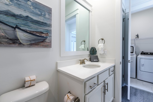 bathroom featuring vanity, hardwood / wood-style flooring, toilet, and washer and dryer