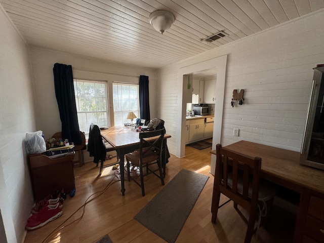 dining room featuring light wood-type flooring and wooden ceiling