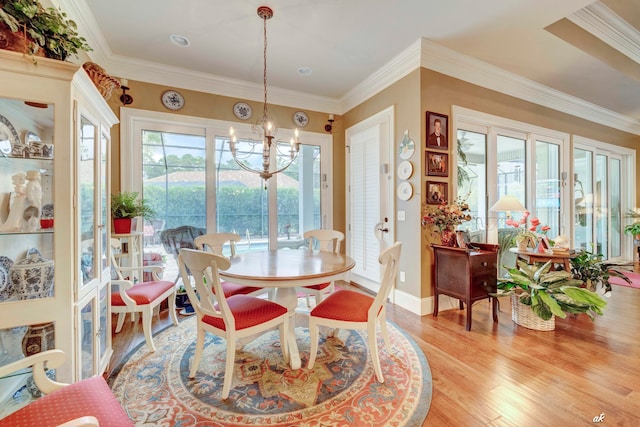 dining room with light hardwood / wood-style floors, ornamental molding, and a chandelier