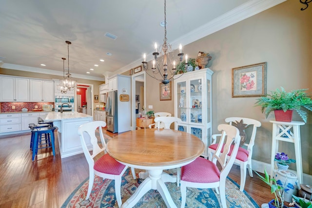 dining space with ornamental molding, dark hardwood / wood-style floors, a notable chandelier, and sink