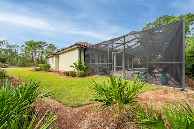 rear view of property with glass enclosure and a lawn