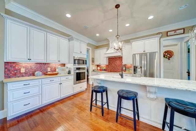 kitchen featuring white cabinetry, pendant lighting, stainless steel appliances, and light hardwood / wood-style flooring