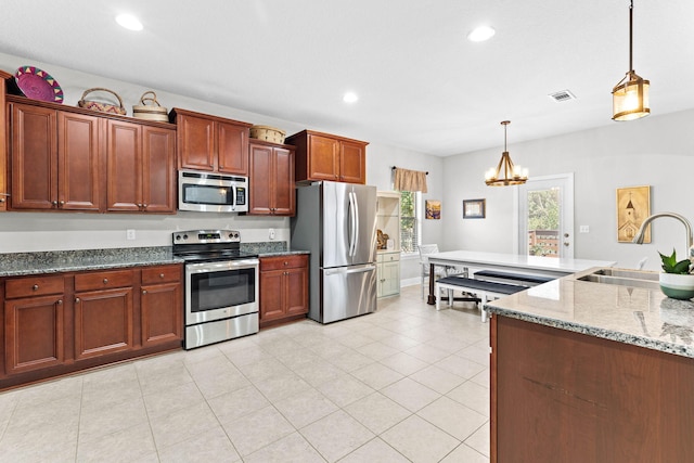 kitchen with light stone counters, stainless steel appliances, sink, pendant lighting, and an inviting chandelier