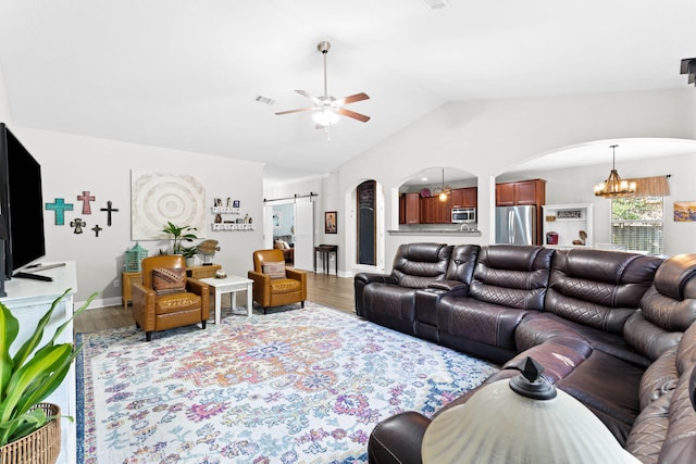 living room featuring ceiling fan with notable chandelier, a barn door, wood-type flooring, and lofted ceiling