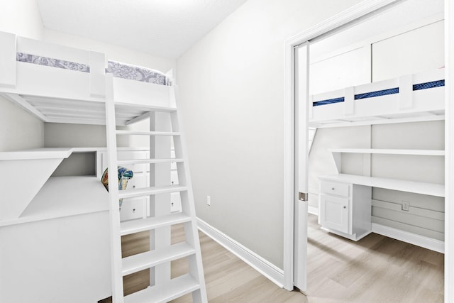 unfurnished bedroom with built in desk, a textured ceiling, and light hardwood / wood-style floors