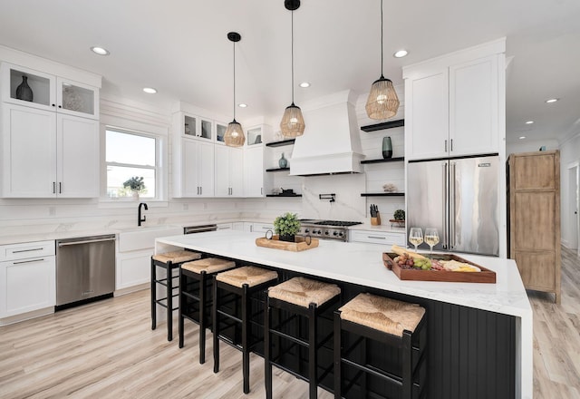 kitchen with appliances with stainless steel finishes, a center island, white cabinetry, and custom range hood