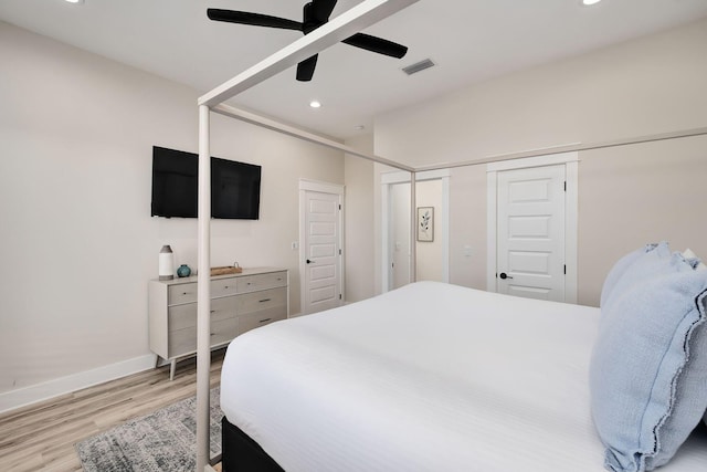 bedroom with two closets, light hardwood / wood-style floors, and ceiling fan