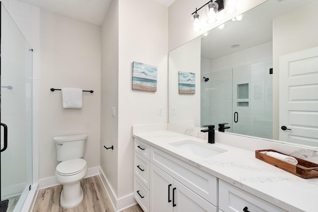 bathroom featuring toilet, vanity, a shower with shower door, and hardwood / wood-style flooring