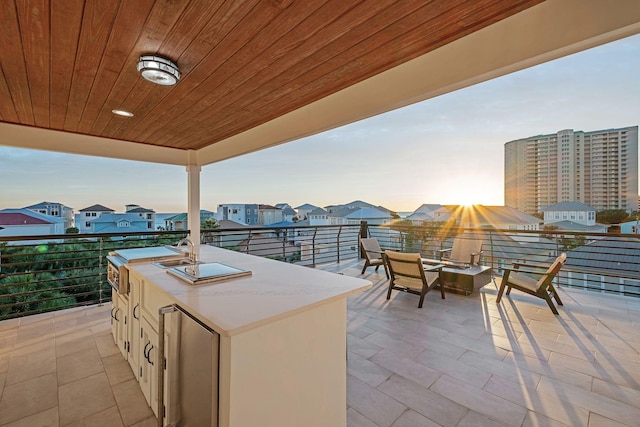 patio terrace at dusk featuring a balcony and sink