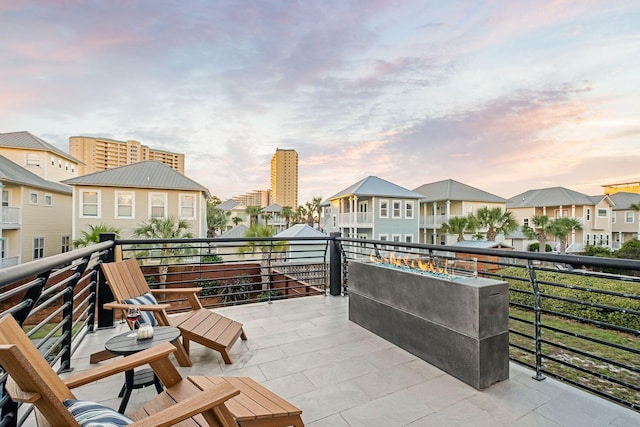 patio terrace at dusk featuring a balcony