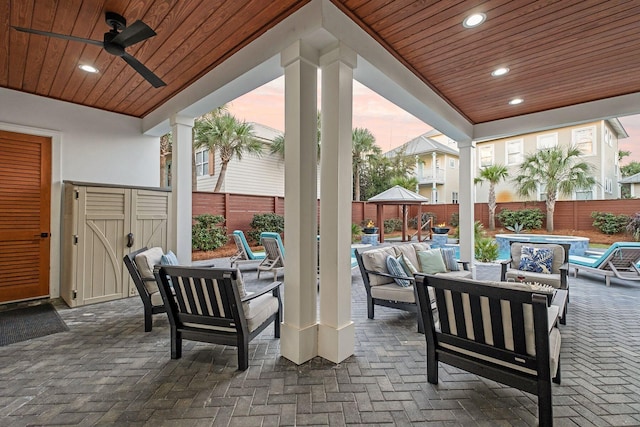 patio terrace at dusk featuring a gazebo, an outdoor living space, and ceiling fan