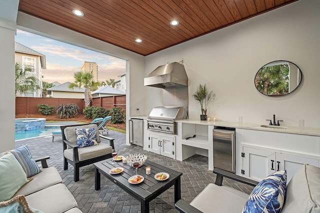 patio terrace at dusk with an outdoor hangout area, sink, exterior kitchen, grilling area, and a fenced in pool