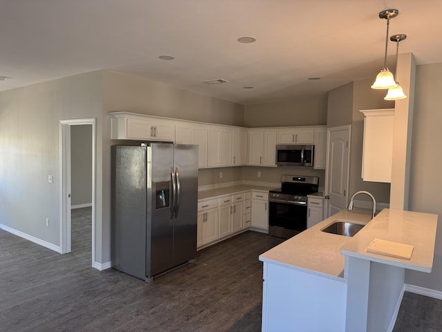 kitchen with appliances with stainless steel finishes, a peninsula, light countertops, white cabinetry, and a sink