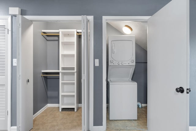 washroom with light tile patterned flooring and stacked washing maching and dryer