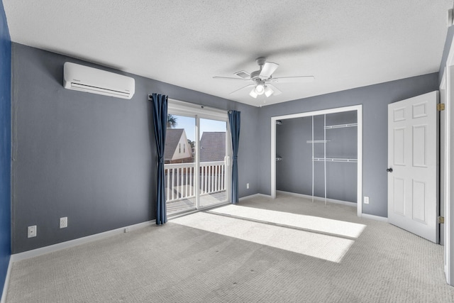 unfurnished bedroom featuring a textured ceiling, access to outside, light colored carpet, a wall mounted AC, and ceiling fan