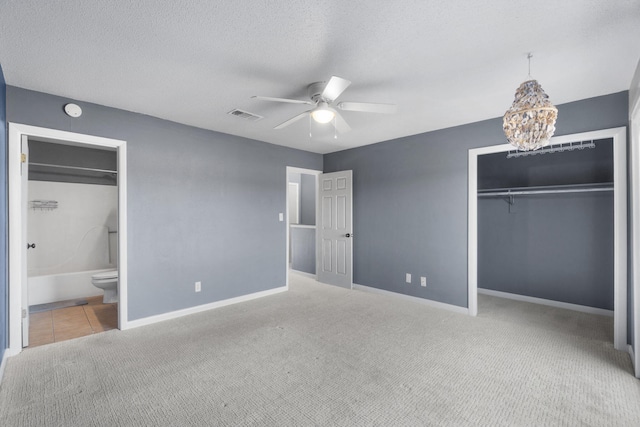 unfurnished bedroom featuring ceiling fan with notable chandelier, a textured ceiling, carpet floors, and ensuite bathroom