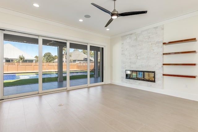 unfurnished living room with ornamental molding, ceiling fan, a fireplace, and light hardwood / wood-style flooring