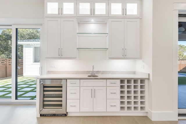 bar featuring white cabinets, sink, and beverage cooler