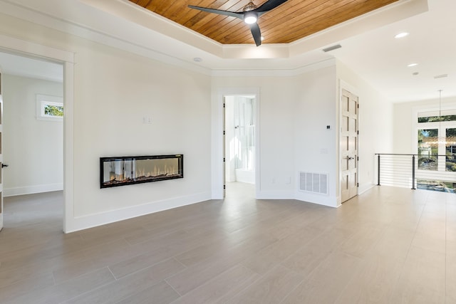 unfurnished living room with ceiling fan, a tray ceiling, and wooden ceiling