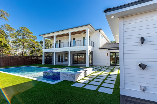 rear view of house with a balcony, a patio area, ceiling fan, and a pool with hot tub