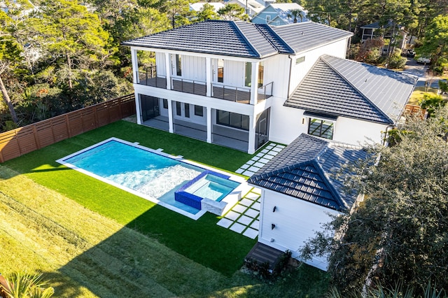 rear view of property featuring a patio area, a balcony, a lawn, a fenced in pool, and a sunroom