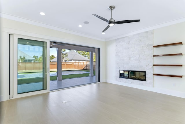 unfurnished living room with crown molding, ceiling fan, and a fireplace