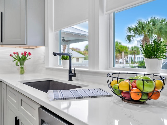 kitchen with tasteful backsplash, light stone countertops, and sink