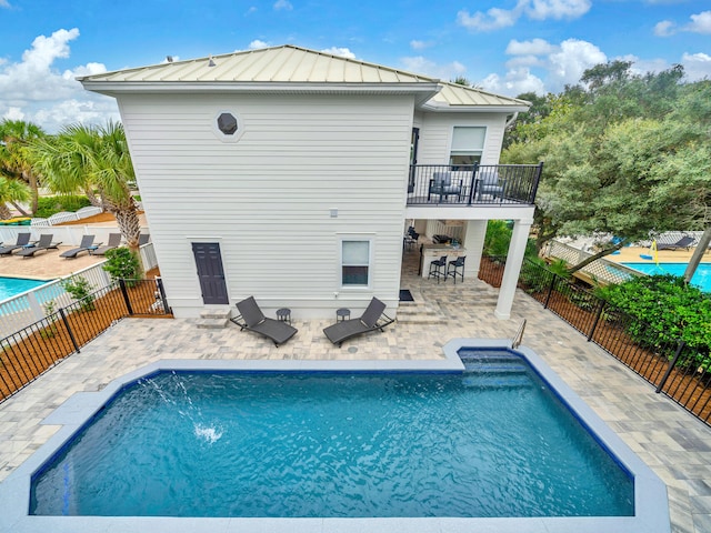 back of house with exterior bar, a fenced in pool, and a patio area