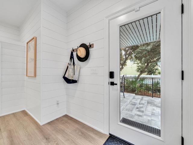 doorway featuring light wood-type flooring and wooden walls