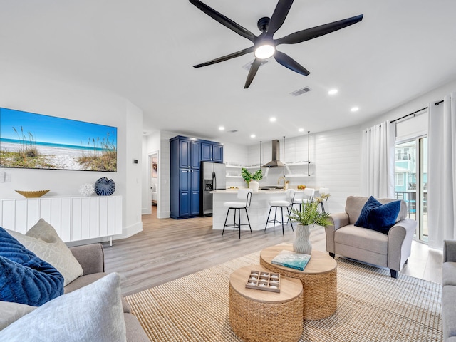 living room featuring light wood-type flooring, ceiling fan, and sink