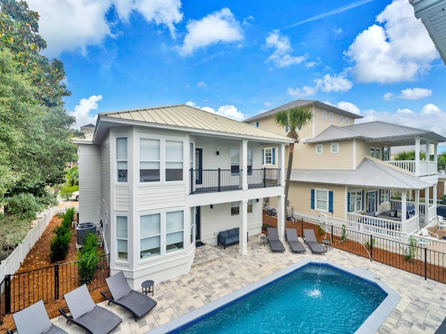 back of house featuring a balcony, a fenced in pool, and pool water feature