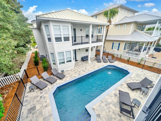 back of house featuring a balcony, a fenced in pool, and a patio area