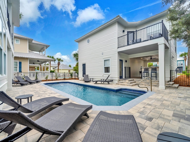 view of swimming pool featuring ceiling fan, a patio, and a bar