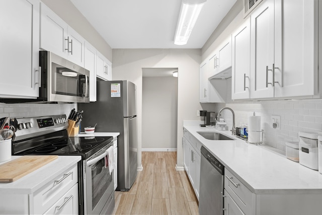 kitchen with white cabinets, stainless steel appliances, sink, and tasteful backsplash