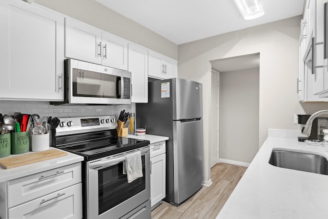 kitchen with white cabinetry, appliances with stainless steel finishes, sink, and tasteful backsplash