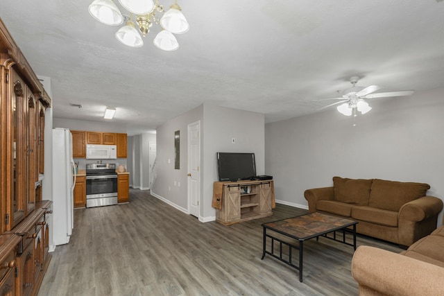 living room with ceiling fan with notable chandelier, wood-type flooring, and a textured ceiling