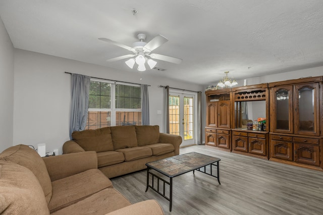 living room featuring a textured ceiling, light hardwood / wood-style floors, and ceiling fan with notable chandelier