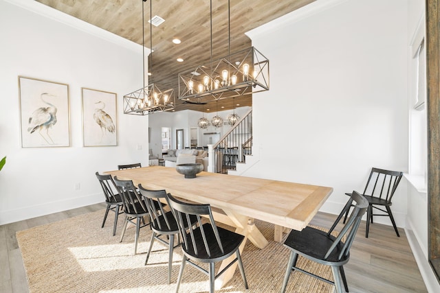 dining room featuring a chandelier, hardwood / wood-style floors, wood ceiling, and a towering ceiling