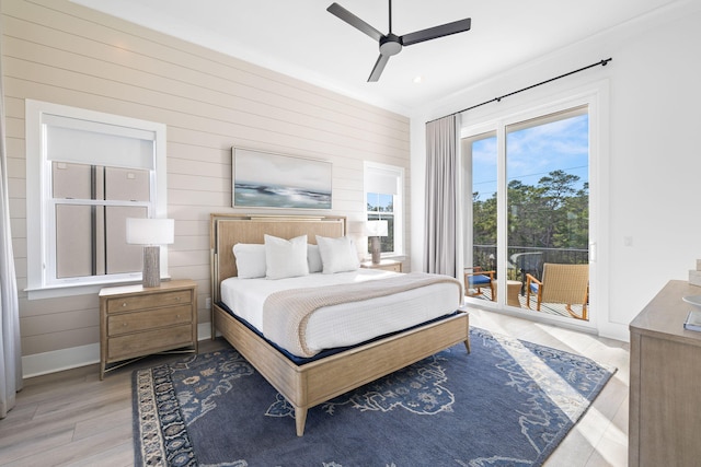 bedroom featuring ceiling fan, wood-type flooring, wood walls, and access to exterior