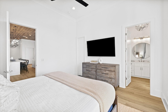 bedroom featuring light hardwood / wood-style flooring, ornamental molding, ceiling fan, and ensuite bathroom